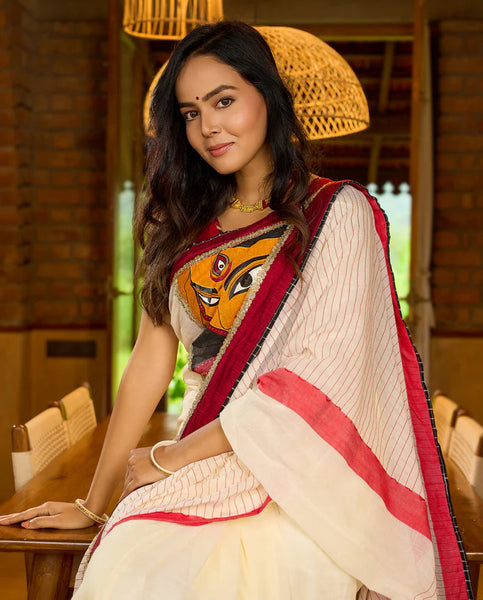 White cotton saree with bold red-black borders, featuring a hand-painted Durga motif
