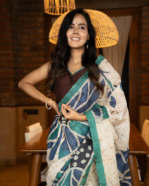 Classic Ivory pure silk saree highlighted by teal borders and hand batik artistry