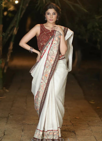 CREAM COTTON BLEND SAREE WITH HANDPAINTED MADHUBANI BORDER HIGHLIGHTED WITH AJRAKH DETAILING